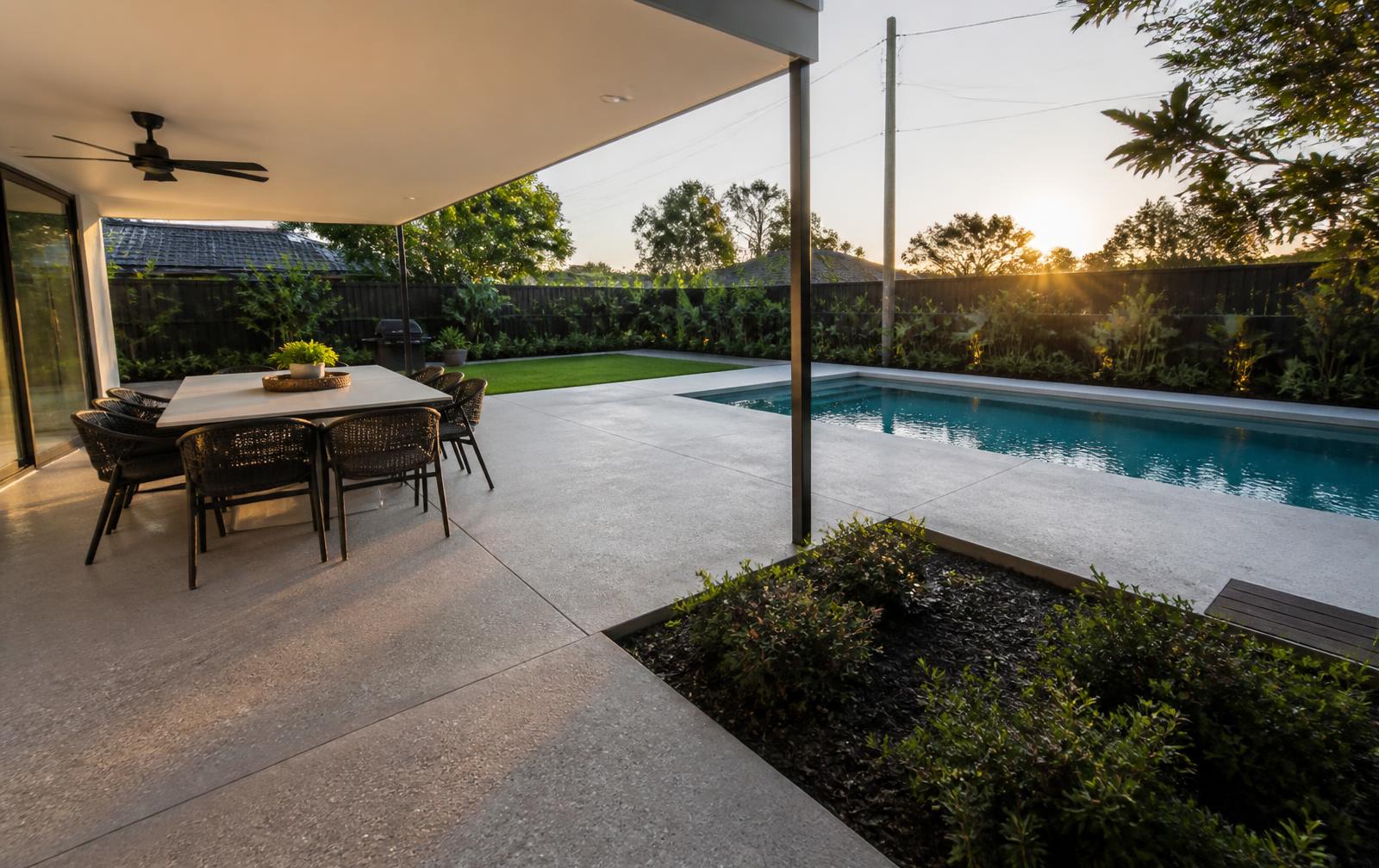 Honed concrete alfresco patio and pool surround in a landscaped backyard